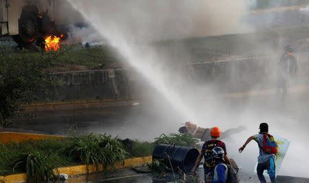 An opposition supporter falls as riot security forces release jets of water from their water cannon during clashes at a rally against Venezuelan President Nicolas Maduro's government in Caracas, Venezuela June 22, 2017. REUTERS/Carlos Garcia Rawlins