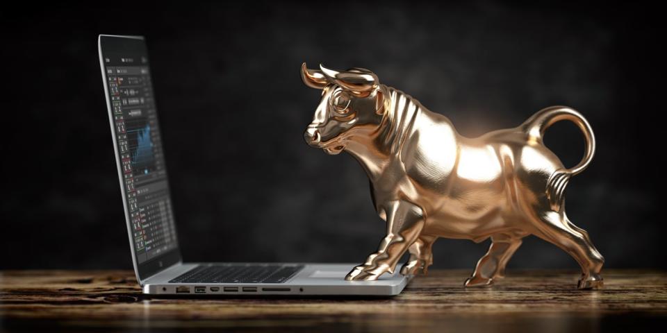 Statue of bull trading stocks on a laptop.