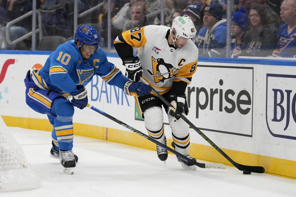 Pittsburgh Penguins' Sidney Crosby (87) and St. Louis Blues' Brayden Schenn (10) chase after a loose puck along the boards during the third period of an NHL hockey game Saturday, Oct. 21, 2023, in St. Louis. (AP Photo/Jeff Roberson)