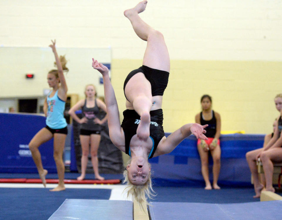 A modern gymnast flies upside down through the air