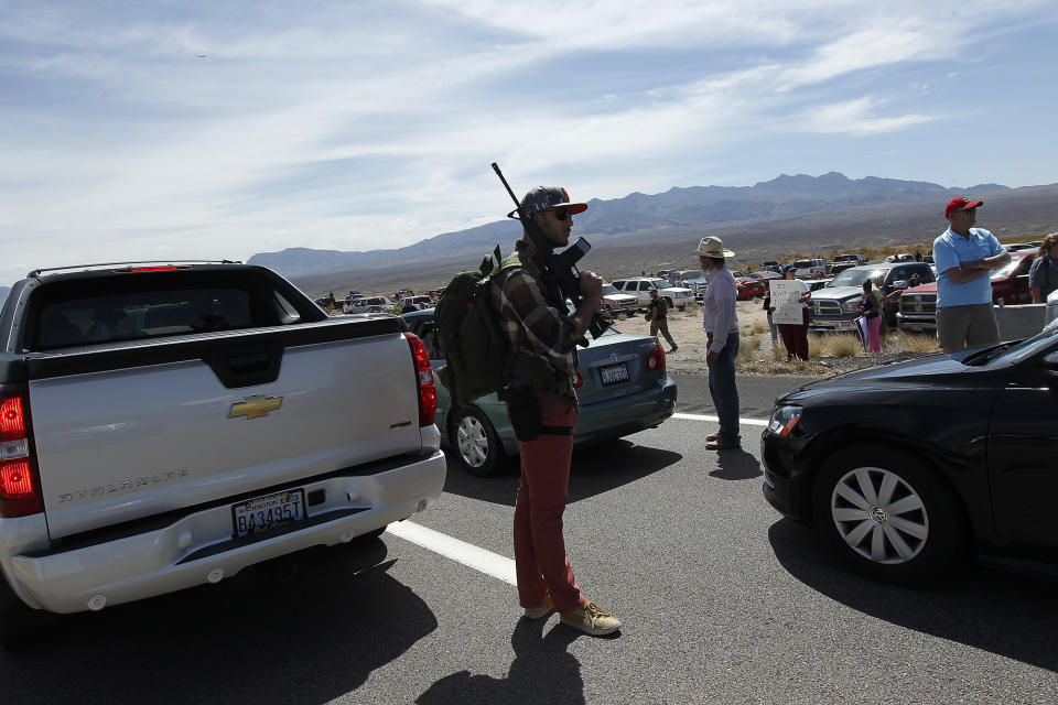 Tyler Lewis, from St. George, Utah, stands in the middle of north bound I-15 with his gun near Bunkerville, Nev. while gathering with other supporters of the Bundy family to challenge the Bureau of Land Management on April 12, 2014. (AP Photo/Las Vegas Review-Journal, Jason Bean)