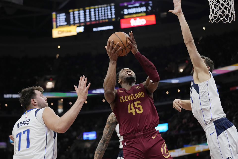 Cleveland Cavaliers guard Donovan Mitchell (45) shoots from between Dallas Mavericks guard Luka Doncic (77) and forward Maxi Kleber during the second half of an NBA basketball game Tuesday, Feb. 27, 2024, in Cleveland. (AP Photo/Sue Ogrocki)