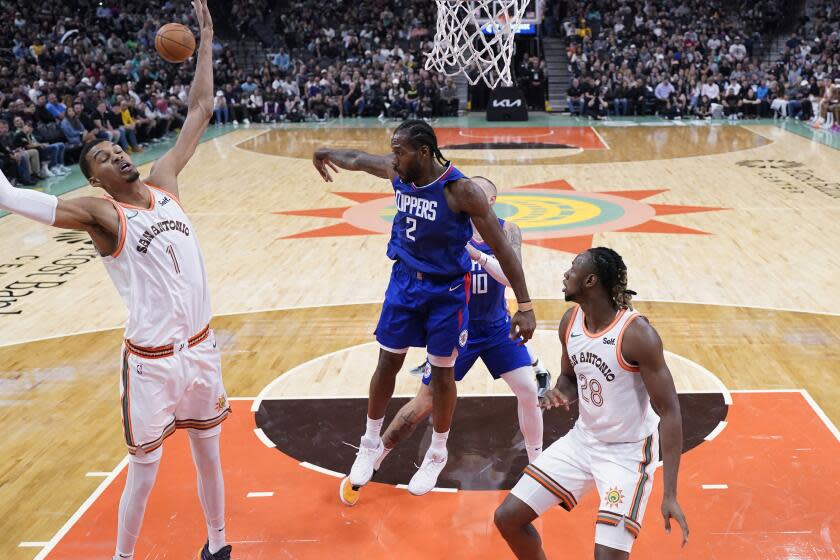 Clippers forward Kawhi Leonard passes the ball around Spurs center Victor Wembanyama