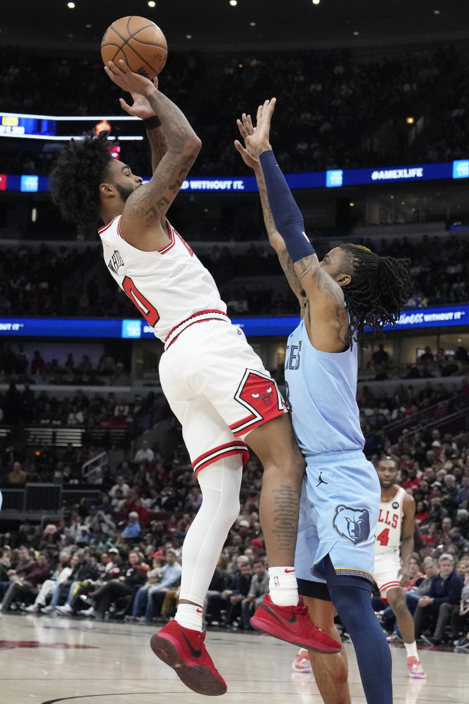 Chicago Bulls guard Coby White, left, shoots over Memphis Grizzlies guard Ja Morant during the first half of an NBA basketball game in Chicago, Sunday, April 2, 2023. (AP Photo/Nam Y. Huh)