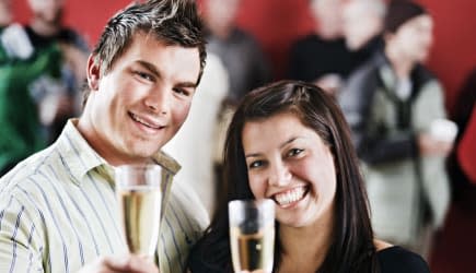 Good looking couple raise glasses in toast at a party