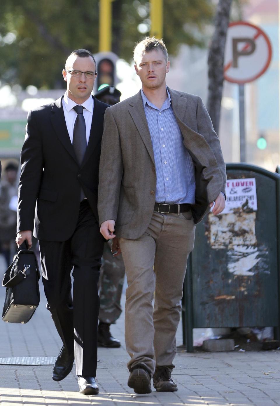 Oscar Pistorius, left, accompanied by an unidentified relative, walks towards the high court in Pretoria, South Africa, Wednesday, May 14, 2014. The chief prosecutor in the murder trial of Pistorius on Tuesday asked that the double-amputee runner be placed under psychiatric evaluation after an expert witness testified that he had an anxiety disorder. Pistorius is charged with murder for the shooting death of his girlfriend, Reeva Steenkamp, on Valentines Day in 2013. (AP Photo/Themba Hadebe)