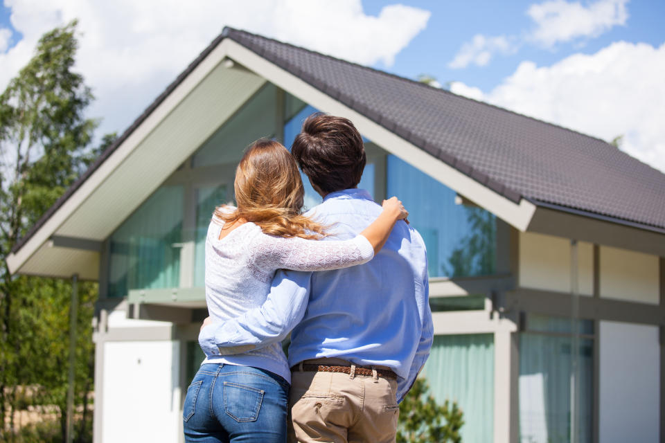 Couple looking at house with arms around one another