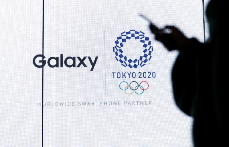 A woman uses her smartphone as an electric screen displaying logos of Tokyo 2020 Olympic Games and Galaxy at Galaxy Harajuku in Tokyo