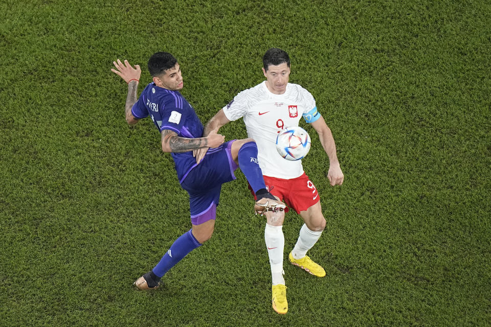 Argentina's Cristian Romero, left, challenges for the ball with Poland's Robert Lewandowski during the World Cup group C soccer match between Poland and Argentina at the Stadium 974 in Doha, Qatar, Wednesday, Nov. 30, 2022. (AP Photo/Pavel Golovkin)