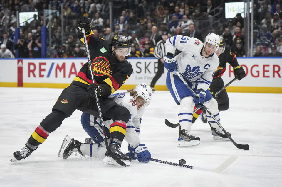 Vancouver Canucks' Carson Soucy, front left, checks Toronto Maple Leafs' William Nylander (88) as Maple Leafs' John Tavares (91) watches during the first period of an NHL hockey game in Vancouver, British Columbia, Saturday, Jan. 20, 2024. (Darryl Dyck/The Canadian Press via AP)