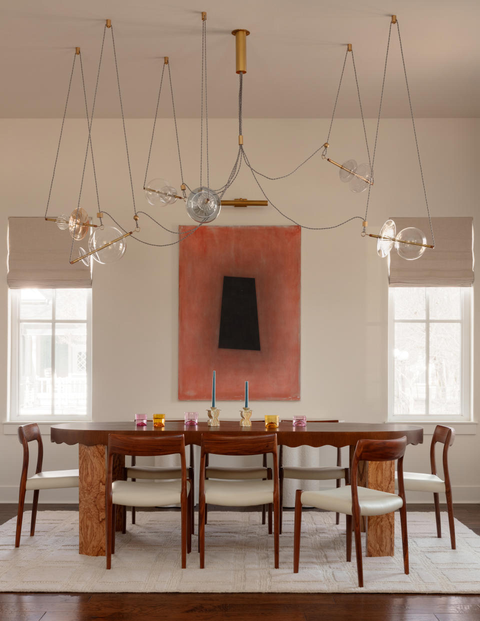 A bright dining room with wired hanging light fixtures and colorful glassware