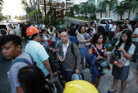 Employees gather outside after evacuating their building following an earthquake in Manila, Philippines Monday, April 22, 2019. A strong earthquake has shaken the area around the Philippine capital, prompting thousands of people to flee to safety. There were no immediate reports of injuries or widespread damage. The U.S. Geological Survey says the magnitude 6.3 quake struck northwest of Manila, Monday, near the town of Gutad on Luzon island. (AP Photo/Aaron Favila)