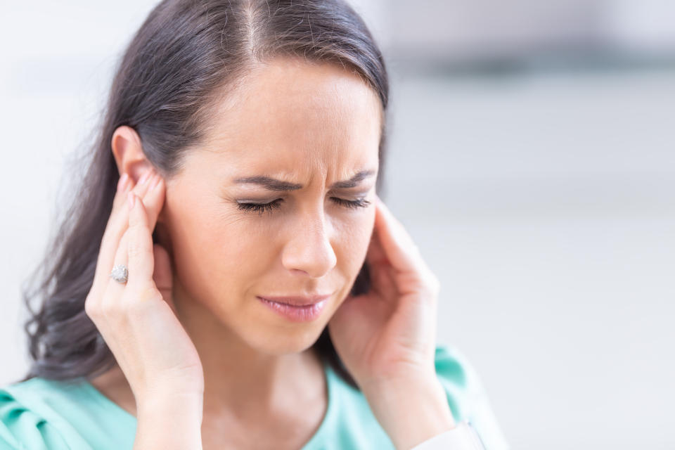 Young woman have headache migraine stress or tinnitus - noise whistling in her ears.