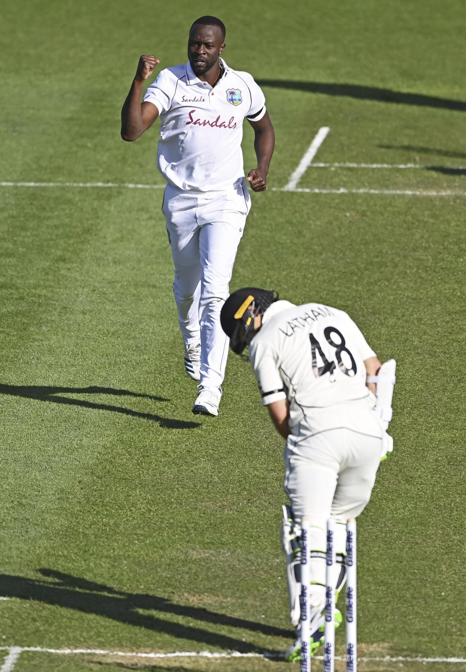 The West Indies Kemar Roach, left, celebrates the wicket of New Zealand's Tom Latham during play on day one of the first cricket test against New Zealand in Hamilton, New Zealand, Thursday, Dec. 3, 2020. (Andrew Cornaga/Photosport via AP)