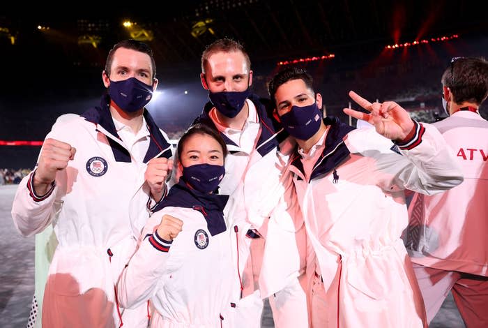 Athletes wearing Team USA white jackets pose at a ceremony while wearing face masks