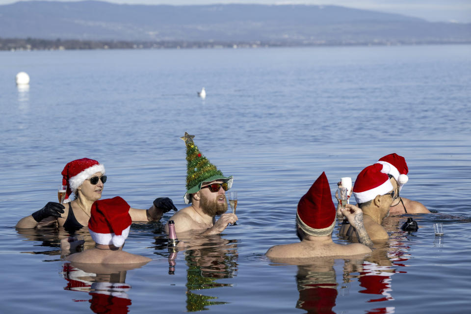 People drink as they swim with Santa hats in 8-degree water in Lake Leman at Bains des Paquis on Christmas Eve, in Geneva, Switzerland, Sunday, Dec. 24, 2023. (Martial Trezzini/Keystone via AP)