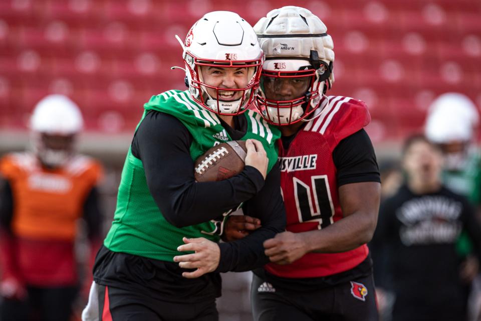 Quarterback Brock Domann, left, tries to protect the football as linebacker Jaylin Alderman tries to knock it loose during a fumble drill at U of L's first spring football practice of 2022 on Monday afternoon. Feb. 28, 2022