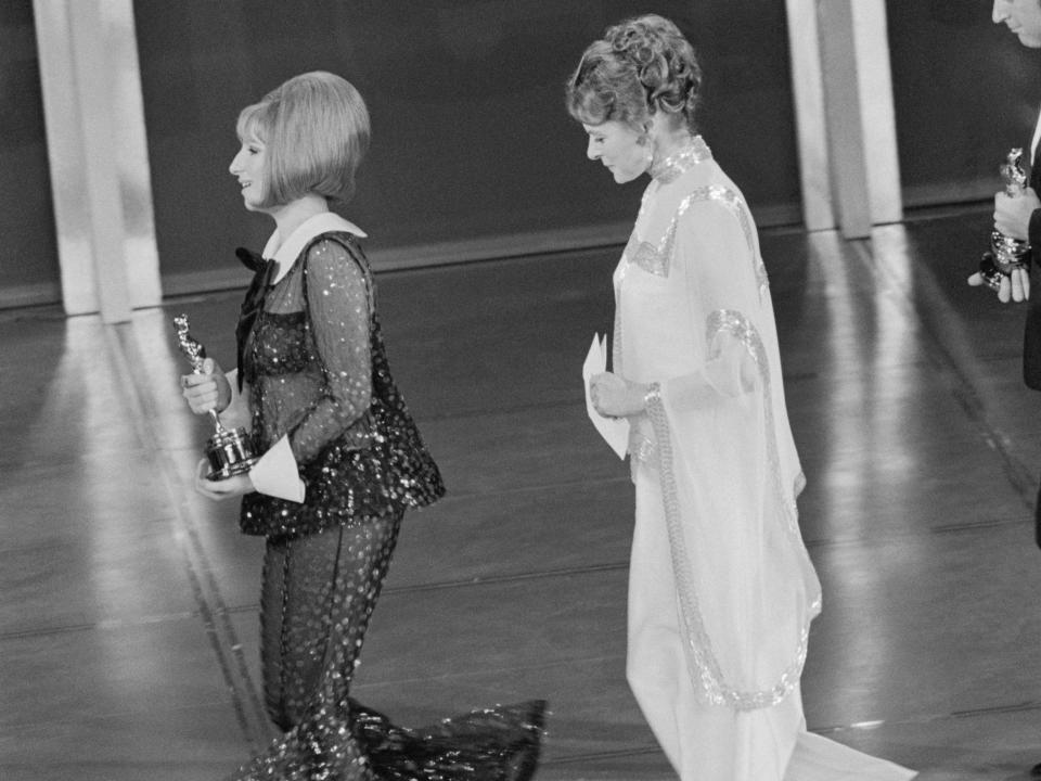 Barbra And Ingrid. Holding her Oscar with both hands, Barbra Streisand walks along the stage and Ingrid Bergman, who made the presentation, follows her at the Acadmy Awards ceremony in Los Angeles, April 14th. Barbra is wearing a black see-through suit.