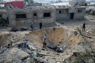 Palestinians inspect a crater on November 14, 2018 caused by an Israeli airstrike in Rafah in the southern Gaza Strip