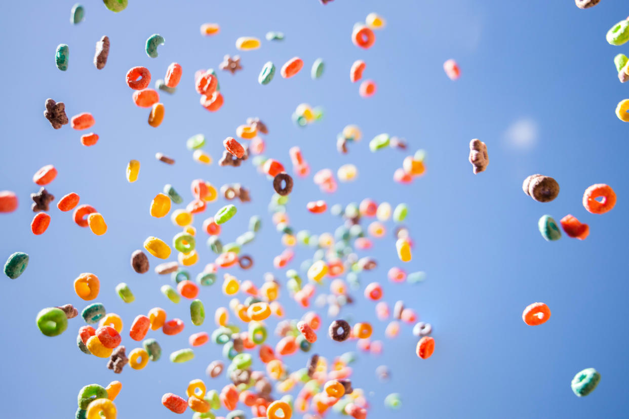 A colorful array of breakfast cereal loops in the air against a blue sky