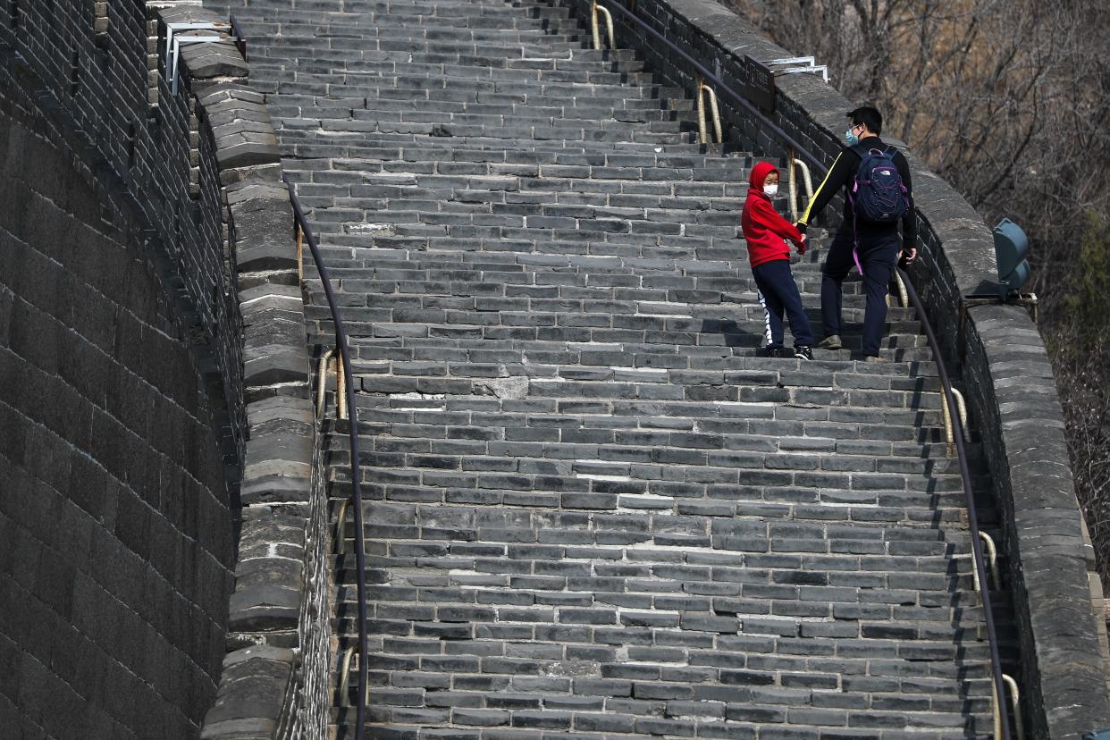 A man and a child wearing protective face masks walk on a stretch of the Great Wall of China after it reopened in Beijing, China on March 24, 2020.