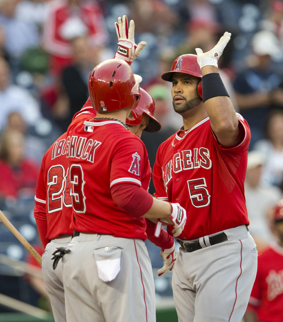 Los Angeles Angels Albert Pujols (5) is greeted at home by teammates J.B. Shuck (3) and Raul Ibanez (28) after hitting a three-run homer off Washington Nationals starting pitcher Taylor Jordan during the first inning of a baseball game in Washington, Tuesday, April 22, 2014. This was Pujos 499th home run of his career. (AP Photo/Pablo Martinez Monsivais)