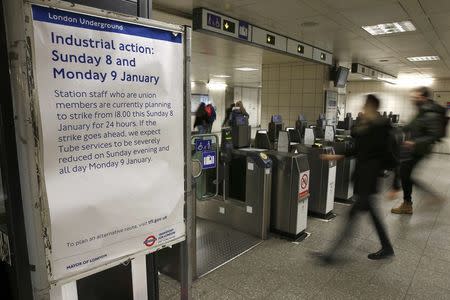 Passengers pass through ticket turnstiles at Waterloo Underground Station next to a notice giving details of a strike involving London Underground workers, in central London January 8, 2017. REUTERS/Peter Nicholls