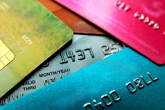 Pile of loosely stacked credit cards, all bright colors with partial number shown.