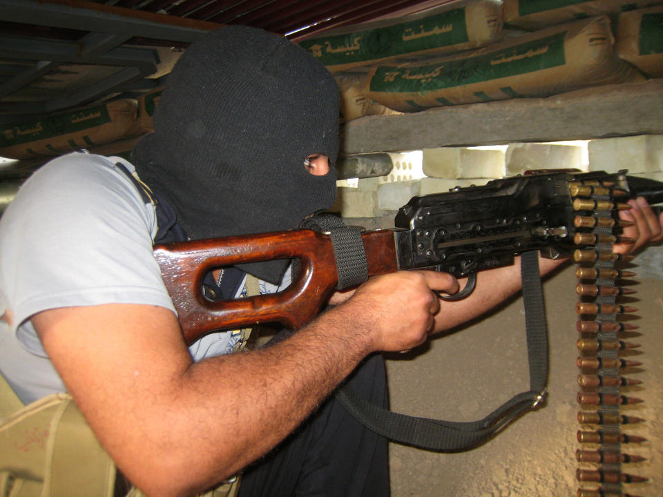 In this Monday, April 28, 2014 photo, a masked anti-government gunman holds his weapon in a combat position in Fallujah, Iraq. Al-Qaida-linked fighters and their allies seized the city of Fallujah and parts of the Anbar provincial capital Ramadi in late December after authorities dismantled a protest camp. Like the camp in the northern Iraqi town of Hawija whose dismantlement in April sparked violent clashes and set off the current upsurge in killing, the Anbar camp was set up by Sunnis angry at what they consider second-class treatment by the Shiite-led government. (AP Photo)