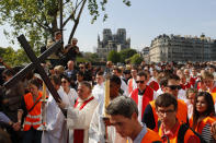 With Notre Dame cathedral in background, religious officials carry the cross during the Good Friday procession, Friday, April 19, 2019 in Paris. Top French art conservation officials say the works inside Notre Dame suffered no major damage in the fire that devastated the cathedral, and the pieces have been removed from the building for their protection.(AP Photo/Francois Mori)