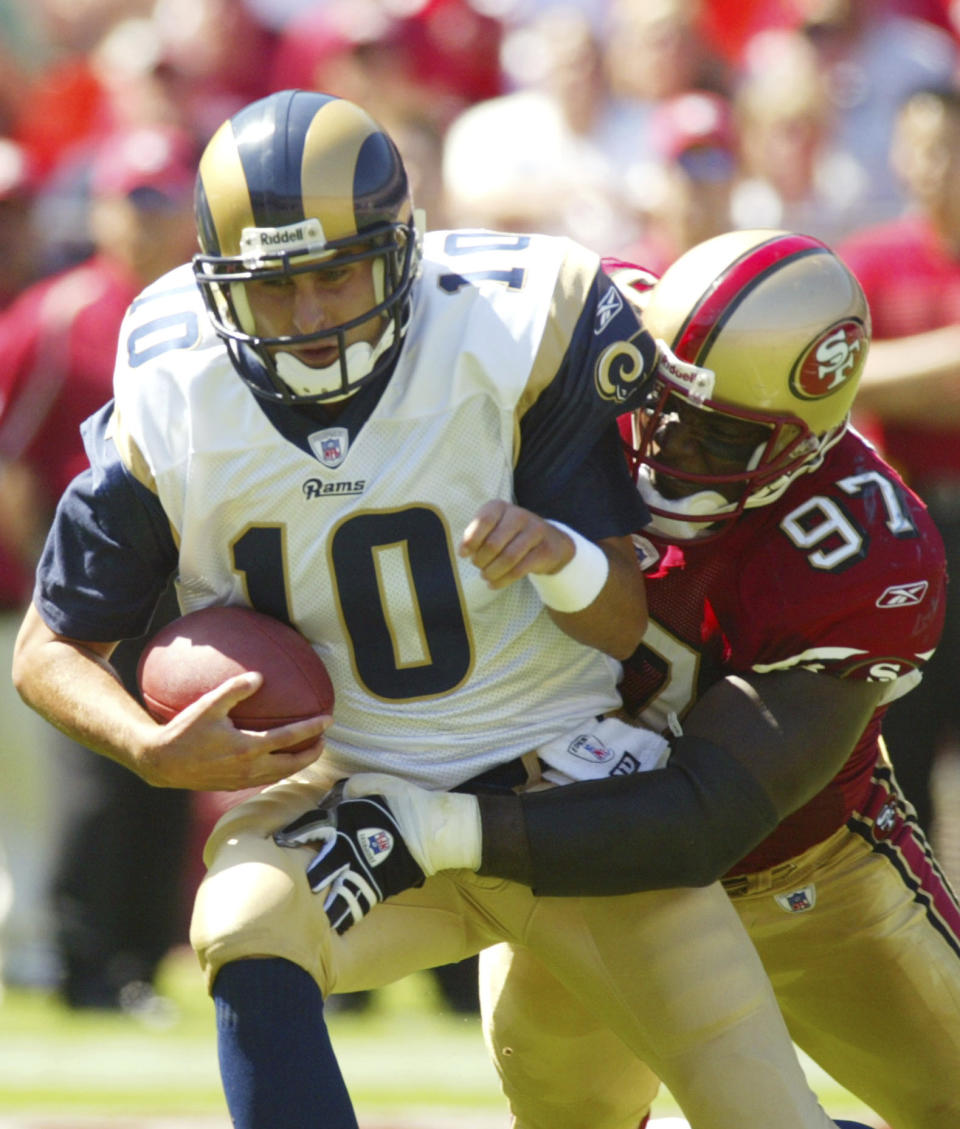 FILE - St. Louis Rams quarterback, Marc Bulger, left, is sacked by San Francisco 49ers Bryant Young during an NFL football game on Sept. 11, 2005 in San Francisco. Young's ability to inspire — both through his play and through his response to unimaginable setbacks on and off the field — finally earned him admission to the Pro Football Hall of Fame this summer, nearly 15 years after his last game. (AP Photo/George Nikitin, File)