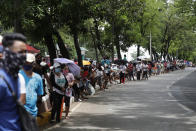 Residents affected by the continuing enhanced community quarantine to prevent the spread of the new coronavirus line up for government cash subsidy along a road in Quezon City, Metro Manila, Philippines on Monday, May 4, 2020. (AP Photo/Aaron Favila)