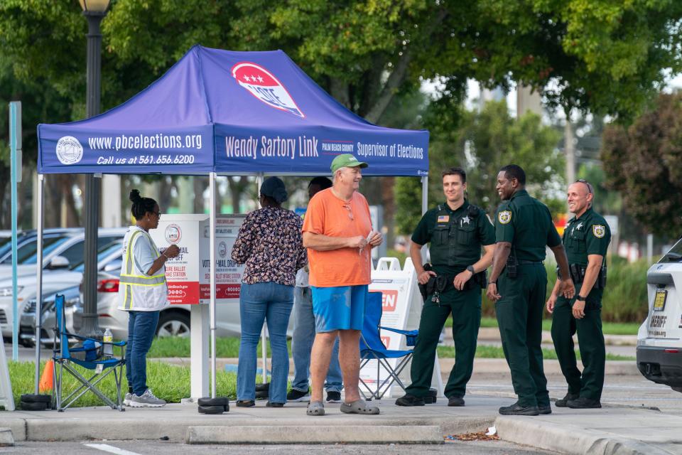 Primary voters deliver their vote-by-mail ballots while Palm Beach County Sheriff's deputies monitor the station at the Supervisor of Elections office in West Palm Beach.