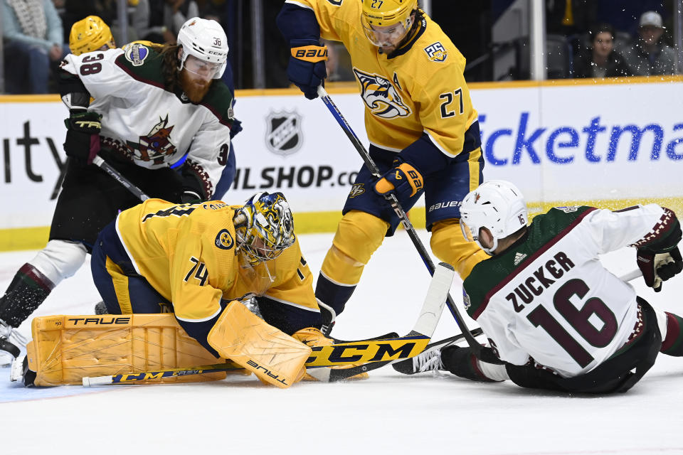 Nashville Predators goaltender Juuse Saros (74) covers the puck as Arizona Coyotes left wing Jason Zucker (16) reaches in during the first period of an NHL hockey game Saturday, Feb. 10, 2024, in Nashville, Tenn. (AP Photo/Mark Zaleski)