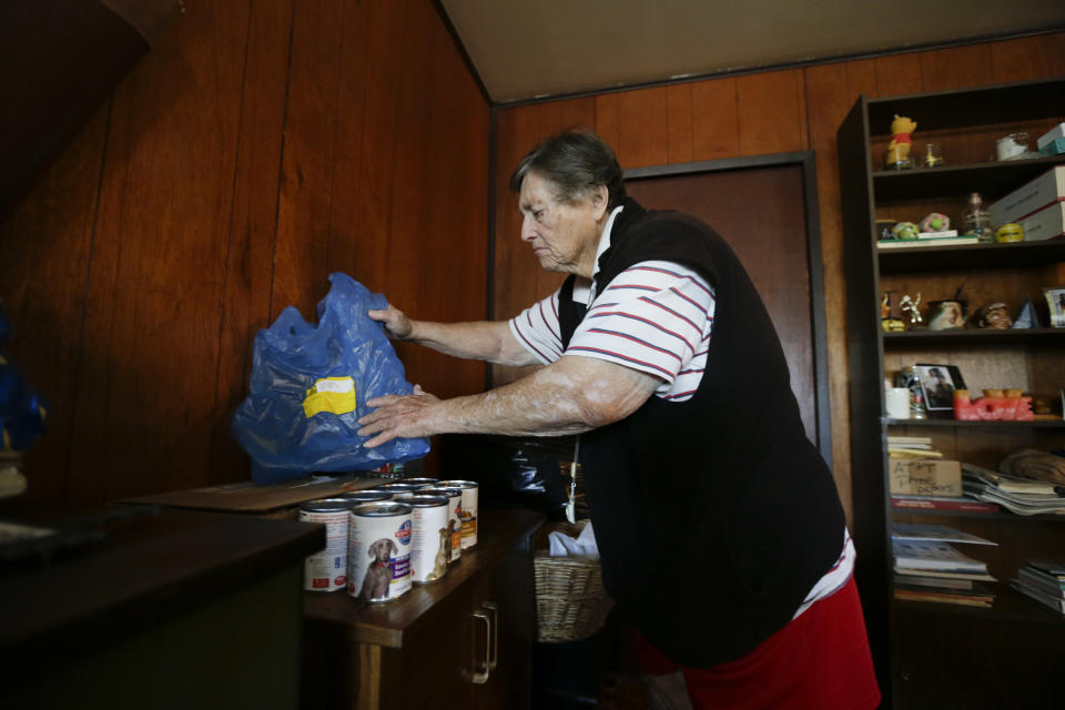 In this Dec. 10, 2013 image, Sherry Scott sorts through the cans of dog food she received through the Animeals program at her home in San Diego. Scott said she would give her lasagne and pork riblets from Meals on Wheels to her 10-year-old golden retriever if MOW didn't bring dog food for the dog. The pet food program is sponsored by the Helen Woodward Animal Center. (AP Photo/Gregory Bull)