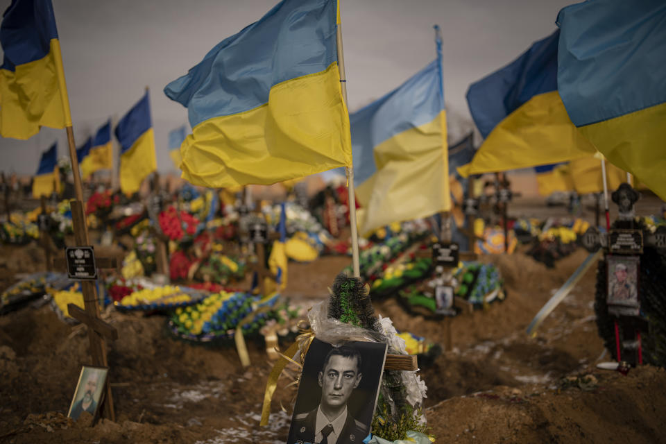 A photograph of a Ukrainian serviceman is placed on his grave in the Alley of Glory part of the cemetery in Kharkiv, Ukraine, Friday, Feb. 24, 2023. Ukraine's leader pledged Friday to push for victory in 2023 as he and other Ukrainians marked the somber anniversary of the Russian invasion that upended their lives and Europe's security. (AP Photo/Vadim Ghirda)