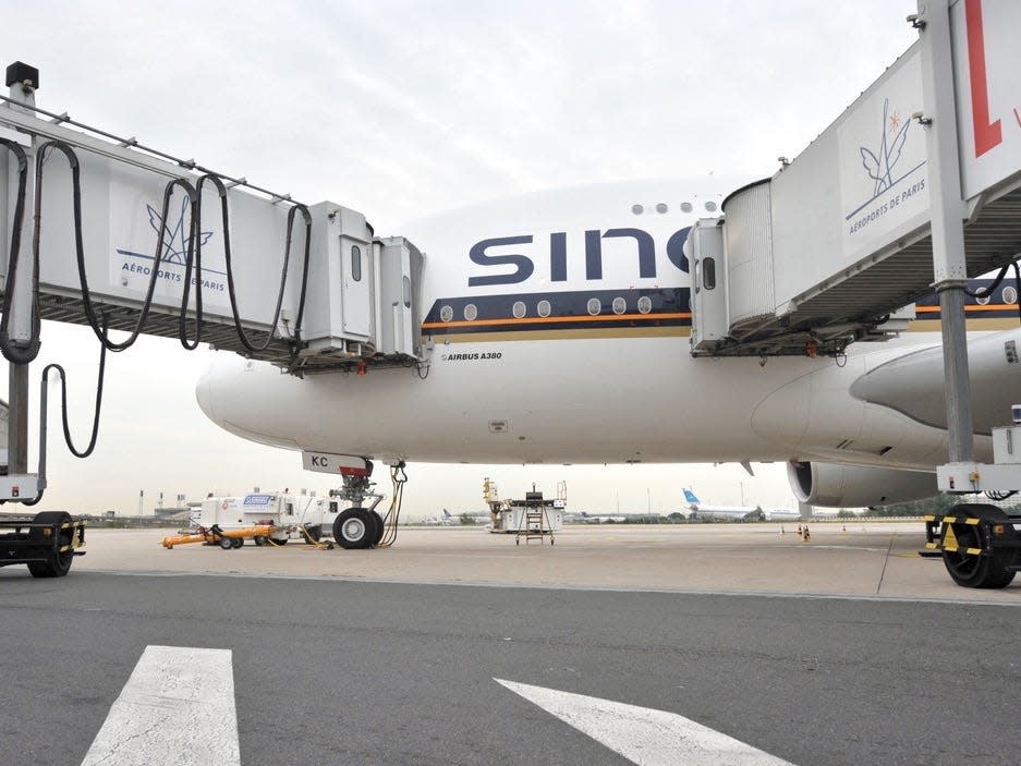 A view of a Singapore A380 being boarded via two lower jetbridges.