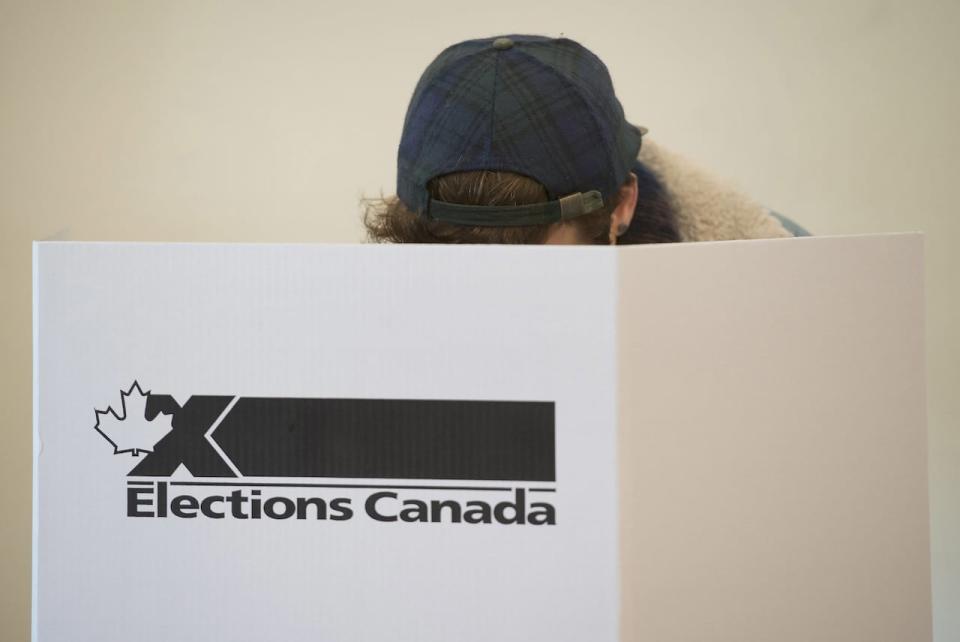 A woman marks her ballot behind a privacy barrier in the riding of Vaudreuil-Soulanges, west of Montreal, on October 19, 2015. Elections Canada has scrapped plans to use social media 