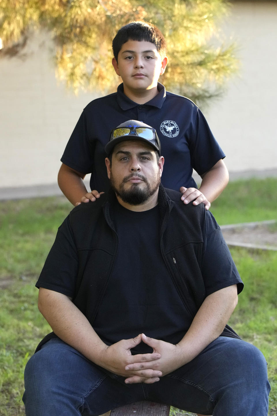 Aaron Galaz and his son pose for an image on Wednesday, Oct. 18, 2023 in Phoenix. Aaron Galaz said his son is enrolled in a program that uses taxpayer funds to pay for private-school tuition in part so his son could be challenged more in class. At least four states that have made most children eligible for taxpayer-funded scholarships to private schools are seeing more families using the programs than planned. That could cost taxpayers, but it's early to know the exact budget implications. (AP Photo/Rick Scuteri)