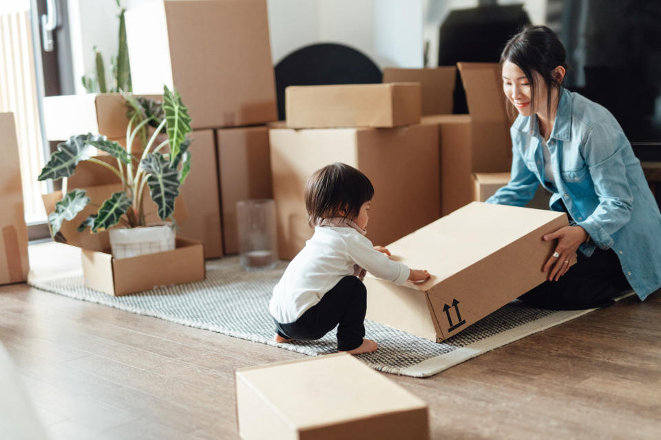 Cute Asian toddler helping her mother to pack, preparing for house moving. Young family feeling excited to move into a new house. New home owner.