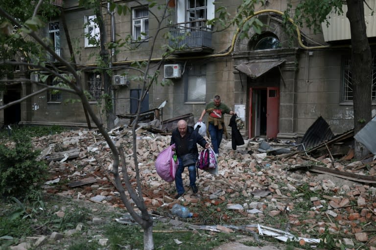 Unos residentes en un edificio atacado con misiles en la ciudad ucraniana de Dnipró sacan sus pertenencias el 19 de abril de 2024 (Anatolii Stepanov)