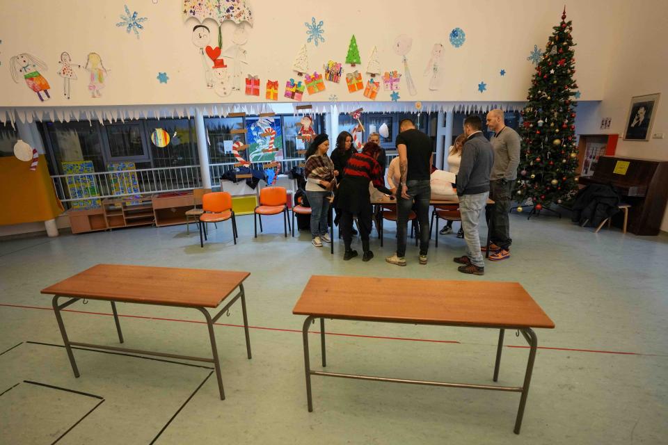 Members of the electoral commission prepare a polling station for a parliamentary and local election in Belgrade, Serbia, Sunday, Dec. 17, 2023. The vote in Serbia pits Serbian President Aleksandar Vucic's governing Serbian Progressive Party, or SNS, against a pro-Western opposition coalition which is trying to undermine the firm grip on power the populists have maintained since 2012. (AP Photo/Darko Vojinovic)