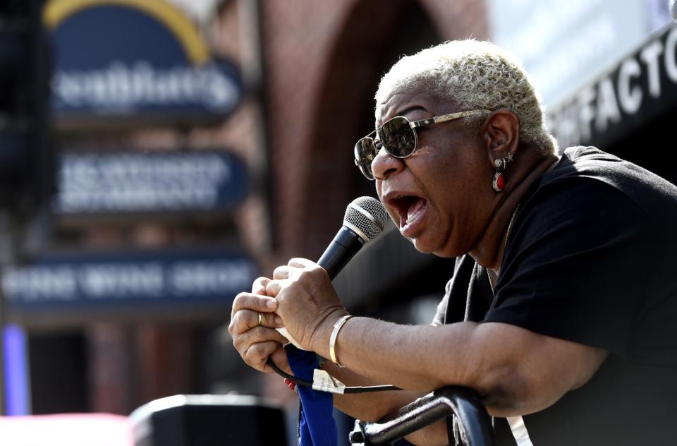 A woman with short gray hair leans on a railing and talks into a microphone