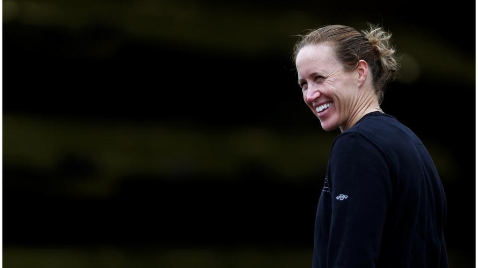 Helen is wearing a navy long sleeve shirt as she smiles towards the left side of the camera