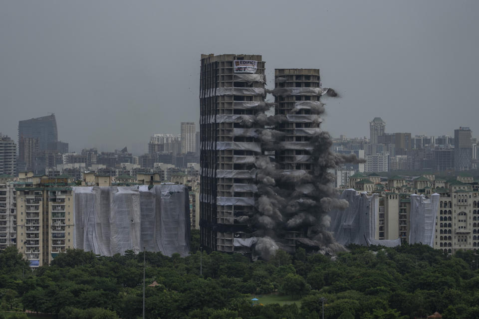 Explosives are detonated to demolish twin high-rise apartment towers in Noida, outskirts of New Delhi, India, Sunday, Aug. 28, 2022. The demolition was done after the country's top court declared them illegal for violating building norms. The 32-story and 29-story towers, constructed by a private builder were yet to be occupied and became India's tallest structures to be razed to the ground. (AP Photo/Altaf Qadri)