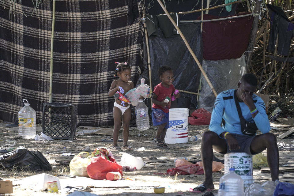 Migrant children play near a man in an encampment under the Del Rio International Bridge where migrants, many from Haiti, have been staying after crossing the Rio Grande, Thursday, Sept. 23, 2021, in Del Rio, Texas. (AP Photo/Julio Cortez)