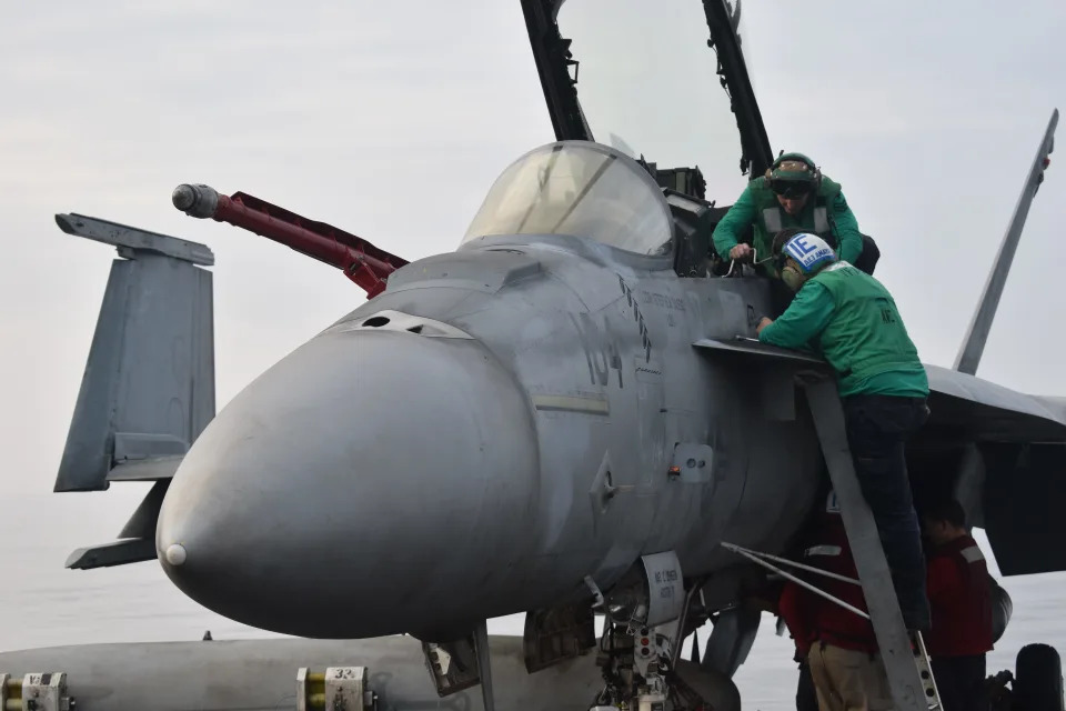 Sailors perform work to a fighter jet on the USS Dwight D. Eisenhower.