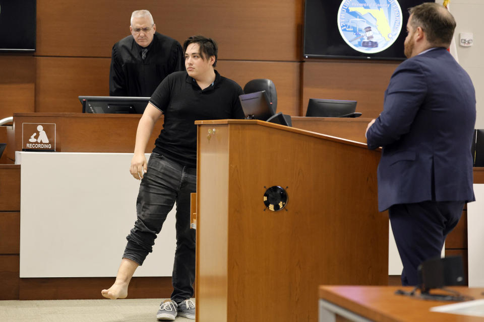 Former Marjory Stoneman Douglas High School student Kyle Laman, who was shot in the 2018 massacre, shows his injured right foot as he testifies on the second day of testimony in the case of former MSD High School School Resource Officer Scot Peterson at the Broward County Courthouse in Fort Lauderdale on Thursday, June 8, 2023. Broward County prosecutors charged Peterson, a former Broward Sheriff's Office deputy, with criminal charges for failing to enter the 1200 Building at the school and confront the shooter as he perpetuated the Valentine's Day 2018 Massacre. (Amy Beth Bennett/South Florida Sun-Sentinel via AP, Pool)