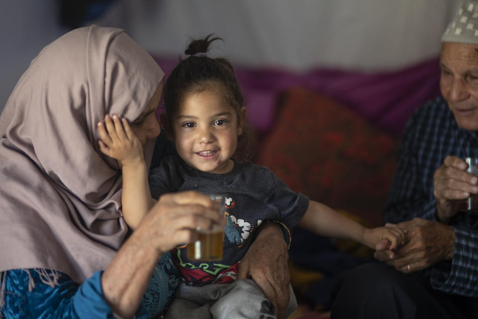 Hocine Azab and his wife Zahrat play with their grand daughter in their tent, after they were displaced by the September earthquake, in Moulay Brahim, outside Marrakech, Morocco, Saturday, Oct. 7, 2023. Morocco has pledged to rebuild from a September earthquake in line with its architectural heritage. Villagers and architects agree that earthquake-safe construction is a top priority. That’s created a push for modern building materials. But the government says it wants to rebuild in line with Morocco’s cultural and architectural heritage. (AP Photo/Mosa'ab Elshamy)