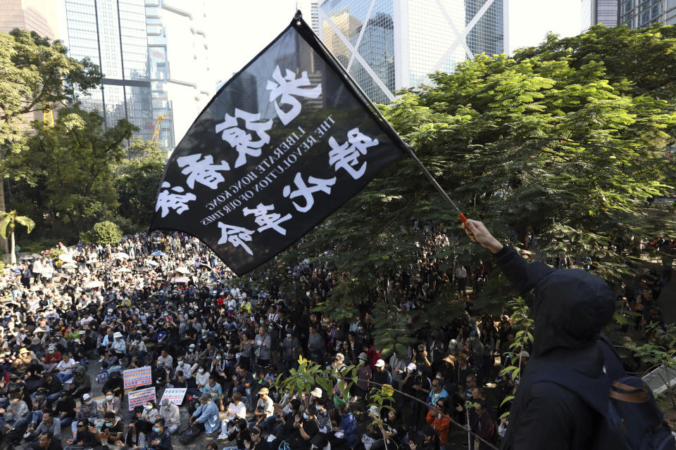 A protester waves a flag reading "Liberate Hong Kong, the Revolution of Our Times" during a rally for students and elderly pro-democracy demonstrators in Hong Kong, Saturday, Nov. 30, 2019. Hundreds of Hong Kong pro-democracy activists rallied Friday outside the British Consulate, urging the city's former colonial ruler to emulate the U.S. and take concrete actions to support their cause, as police ended a blockade of a university campus after 12 days. (AP Photo/Ng Han Guan)